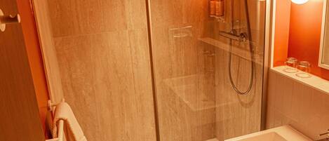 A bathroom with a glass-enclosed shower, a white sink, and a mirror with wall-mounted lights.