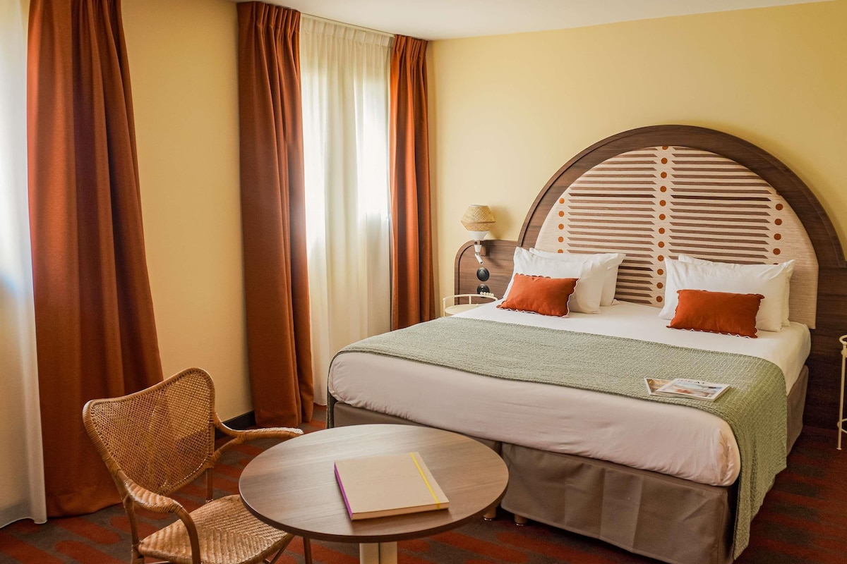 Una habitación de hotel con una cama, una mesa redonda, una silla y una lámpara.