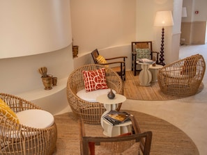 A cozy lounge area with wicker furniture, a small table with a book, and a lamp. - Mercure Arles Centre Arenes (Arles)