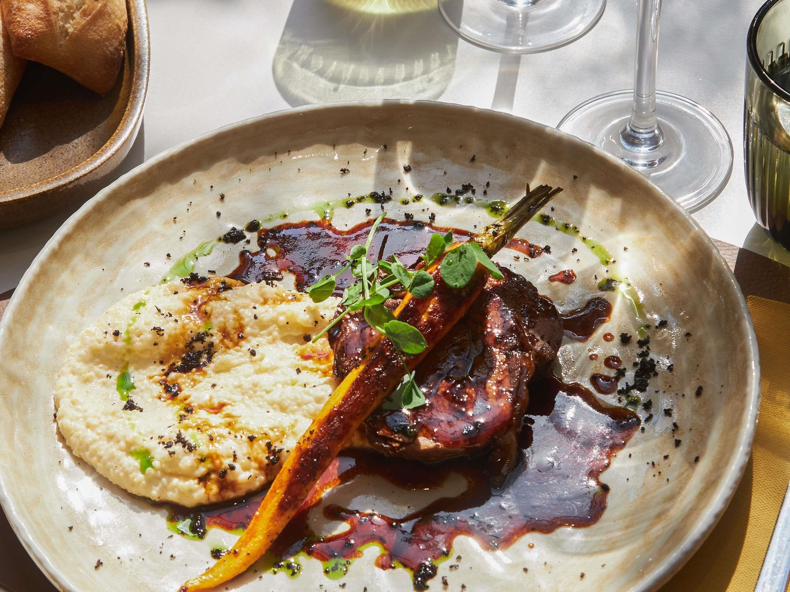 A plate of food with a steak, mashed potatoes, and a garnish.