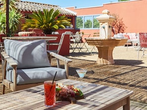 An outdoor seating area with a table, chairs, a drink, and a small fountain. - Mercure Arles Centre Arenes (Arles)