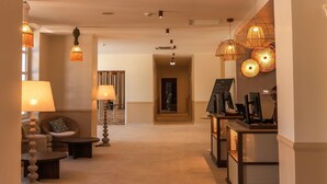 A hotel lobby with a central seating area, a reception desk, and a staircase leading to another floor. - Mercure Arles Centre Arenes (Arles)