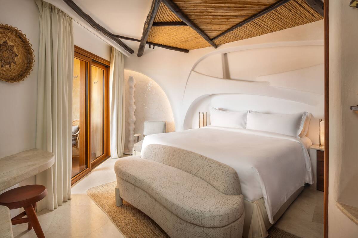 Une chambre à coucher moderne avec un grand lit, un petit coin salon et une vue sur l’extérieur.