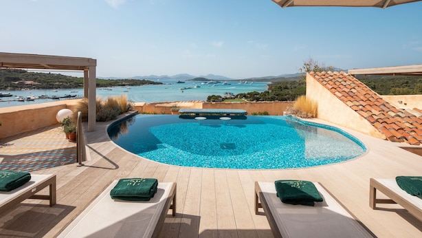 A pool area with lounge chairs and a pergola, overlooking a coastal landscape with boats. - Cala di Volpe, a Luxury Collection Hotel, Costa Smeralda (Arzachena)