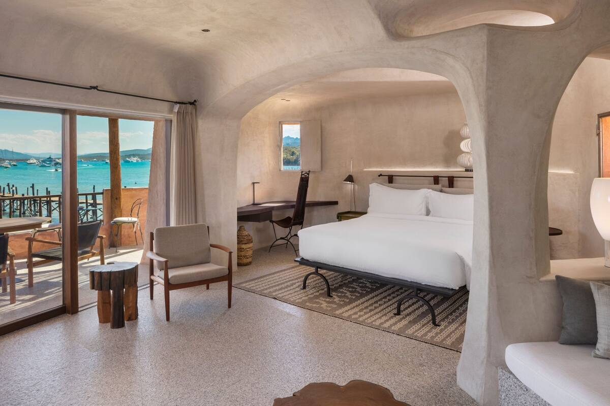 Une chambre d’hôtel moderne avec un grand lit, un bureau et une vue sur la mer.