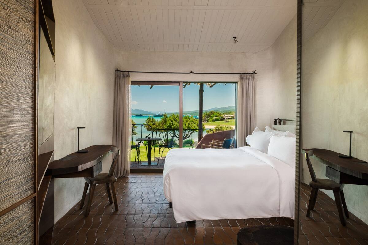 Une chambre avec un grand lit, un bureau et une vue sur la mer.