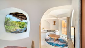 A modern interior with a view of greenery outside, a wooden table, and a seating area with a patterned rug. - Cala di Volpe, a Luxury Collection Hotel, Costa Smeralda (Arzachena)