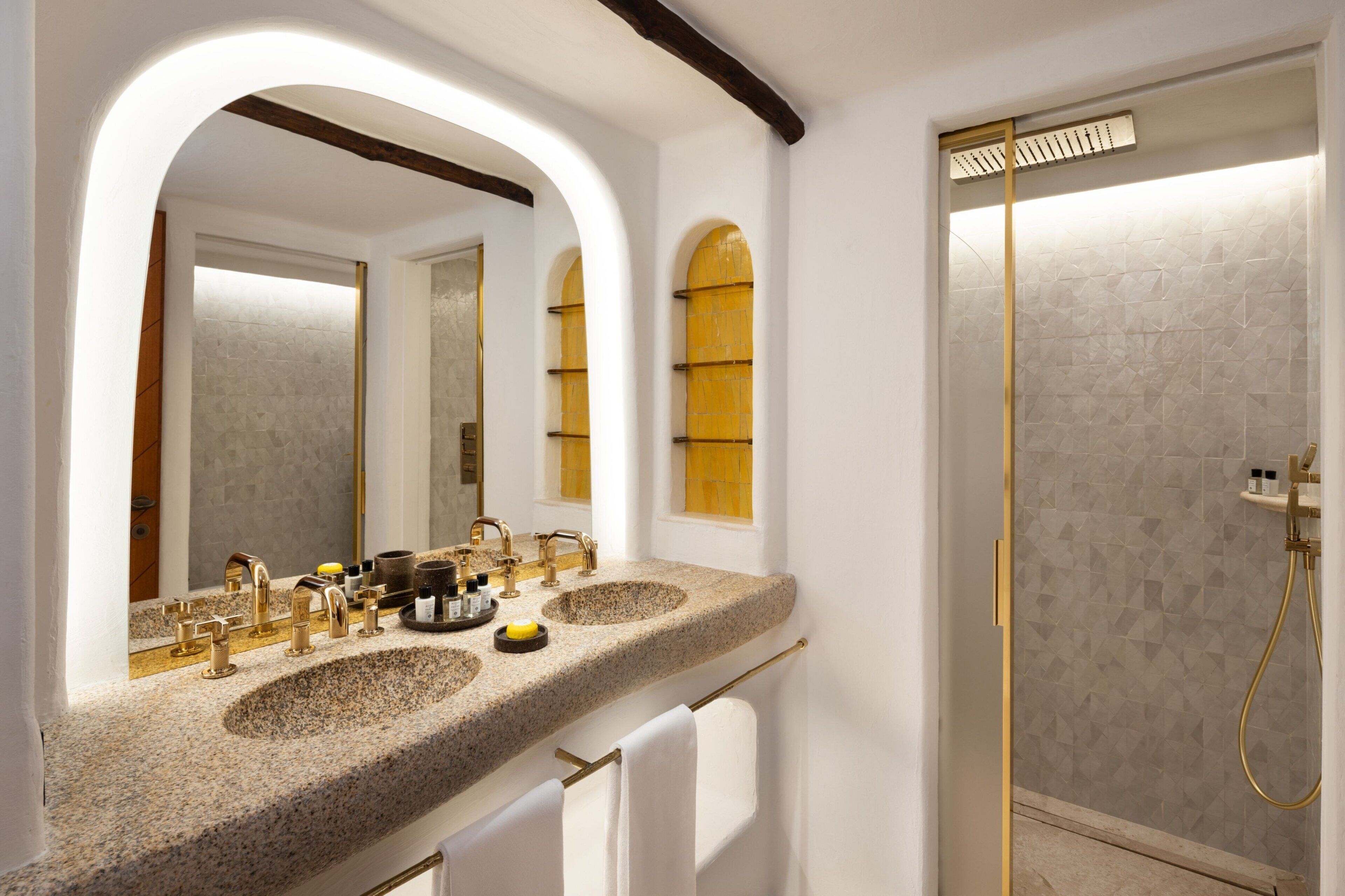 A bathroom with two sinks, a shower, and a vanity mirror.