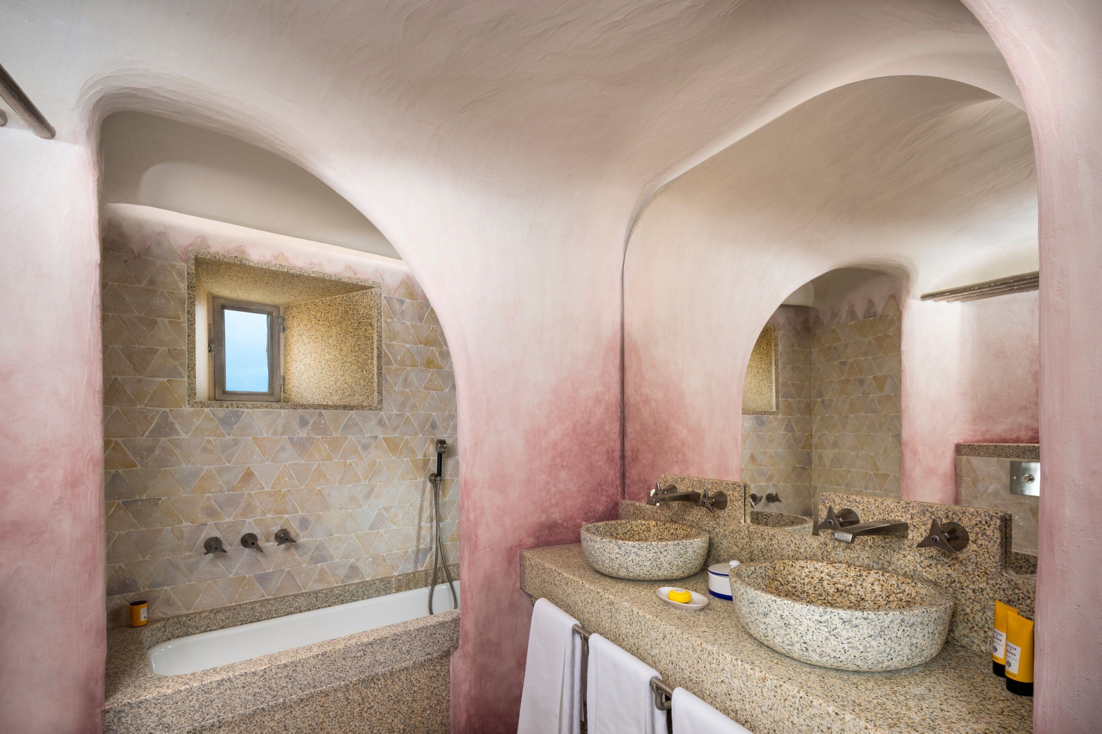 Un baño con dos lavamanos de granito, una bañera y una ducha.