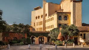 A historic building with a courtyard, arched doorways, and a tiled roof. - Cala di Volpe, a Luxury Collection Hotel, Costa Smeralda (Arzachena)