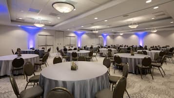 Un amplio salón de conferencias con varias mesas redondas y sillas, dispuestas en forma de U.