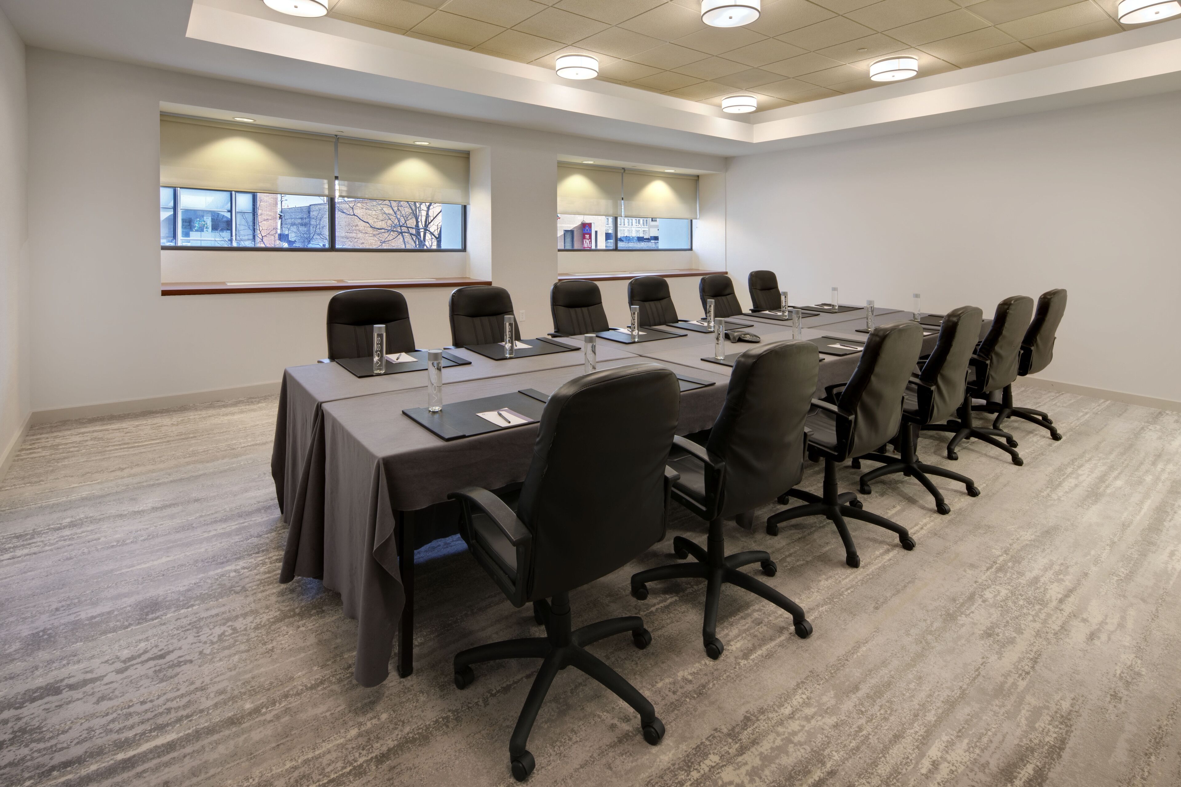 A conference room with a long table, black chairs, and a carpeted floor.