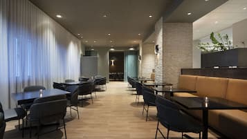 A modern hotel lobby with a long corridor, seating areas, and a stone accent wall.
