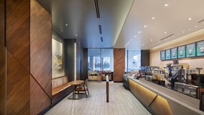 A modern cafe interior with wooden accents, a seating area, a counter with a coffee machine, and a menu board.