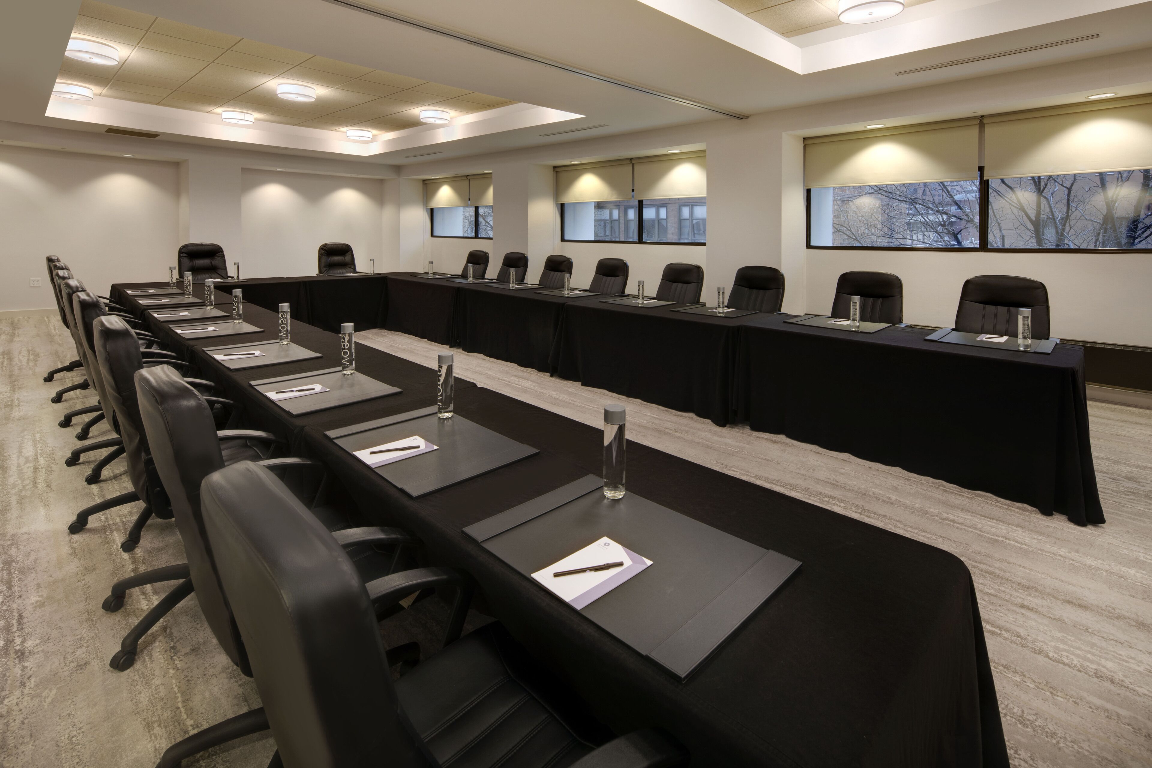 Ein Konferenzraum mit einem langen Tisch, mehreren Stühlen und einer schwarzen Tischdecke.