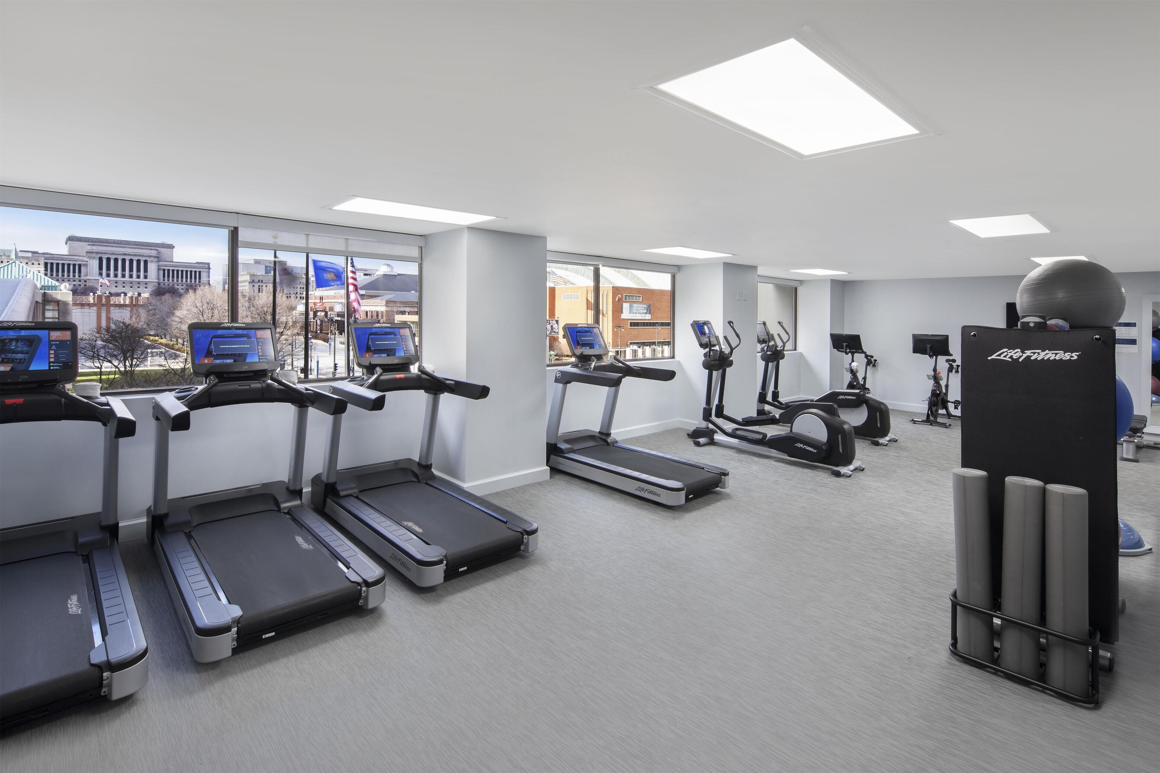 A gym with treadmills, elliptical machines, and a Life Fitness ball.