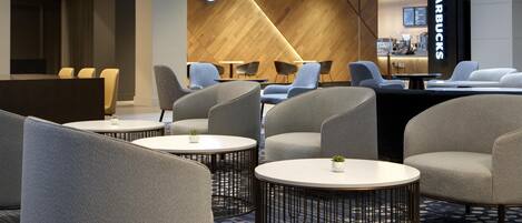 A modern interior with round tables and chairs, a Starbucks sign, and a counter area.