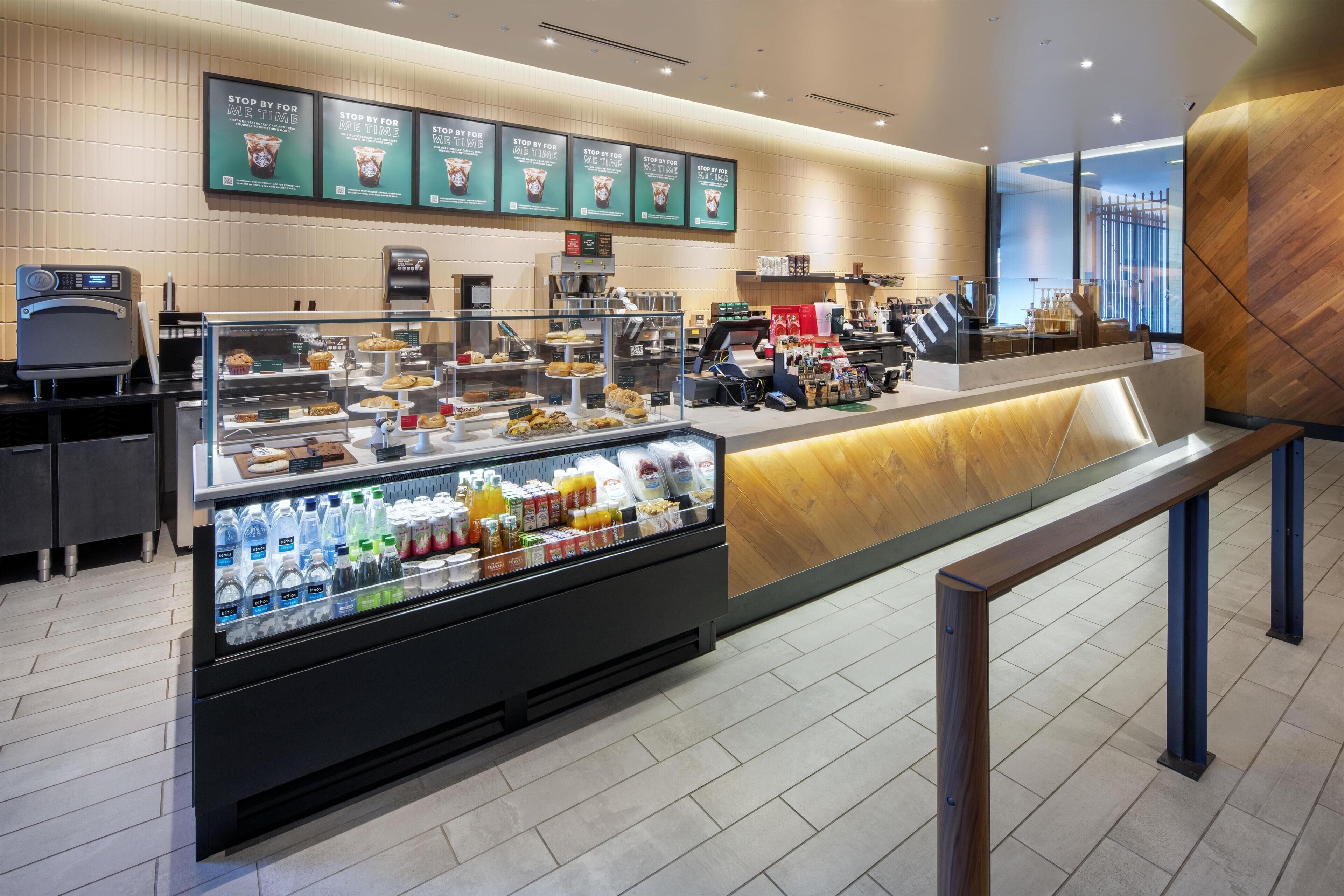 Una caffetteria moderna con un bancone self-service, una vetrina refrigerata per bevande e una bacheca con il menu.