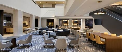 A spacious lobby with a high ceiling, multiple seating areas, and a central coffee table.