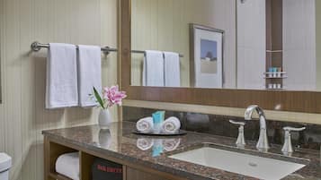 A modern bathroom with a marble countertop, a sink, a mirror, and a towel rack.