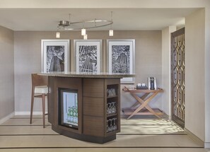 A modern bar area with a wooden counter, a refrigerator with bottles, and framed pictures on the wall. - Hyatt Regency Milwaukee (Milwaukee)