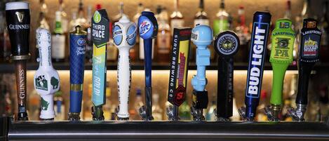 Un bar con diferentes grifos de cerveza, incluyendo marcas como Guinness, Bud Light y Third Space Brewing.