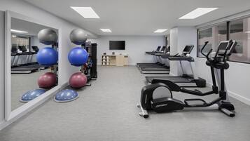 A gym with treadmills, elliptical machines, and exercise balls.