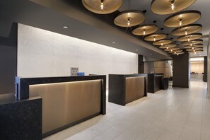 A modern hotel reception area with a central desk, multiple reception counters, and a decorative ceiling with circular light fixtures. - Hyatt Regency Milwaukee (Milwaukee)