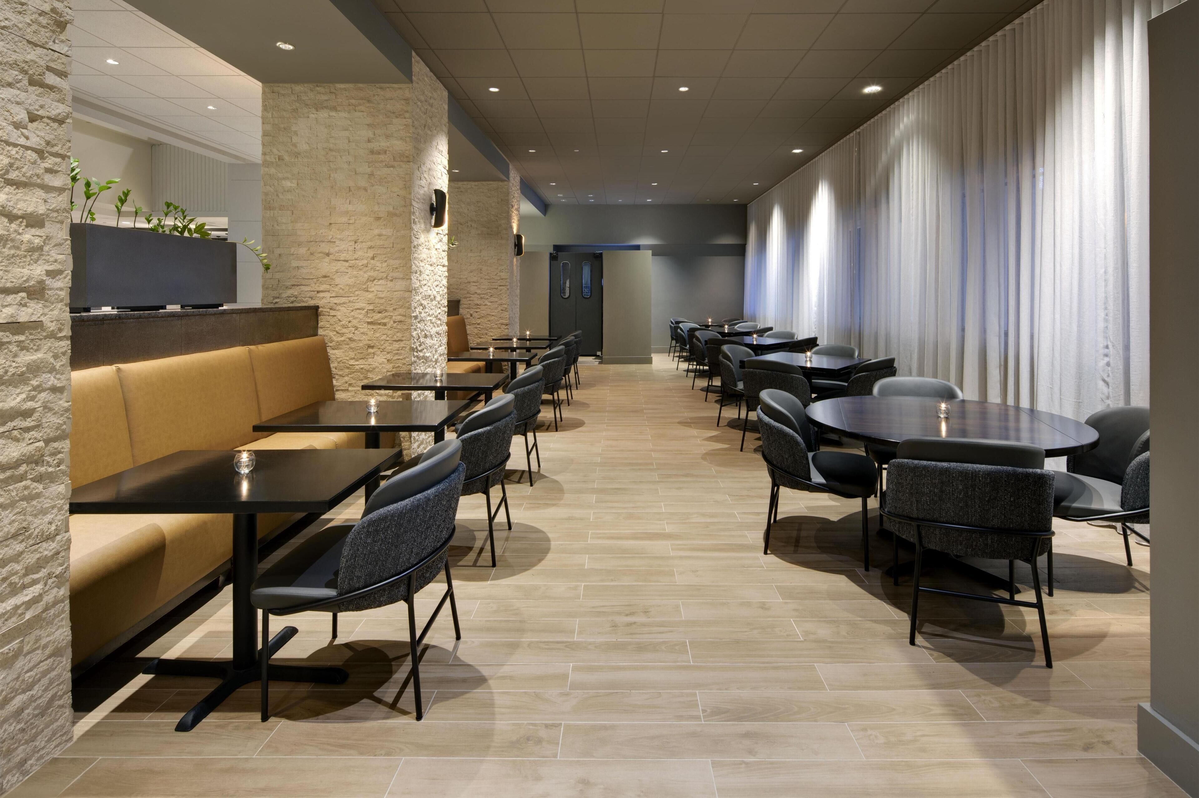 A modern dining area with a mix of booths and tables, stone accents on the walls, and a neutral color palette.