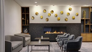A modern lounge area with sofas, armchairs, a fireplace, and decorative wall art.