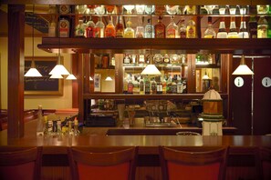 A bar area with a variety of liquor bottles, a coffee machine, and seating.