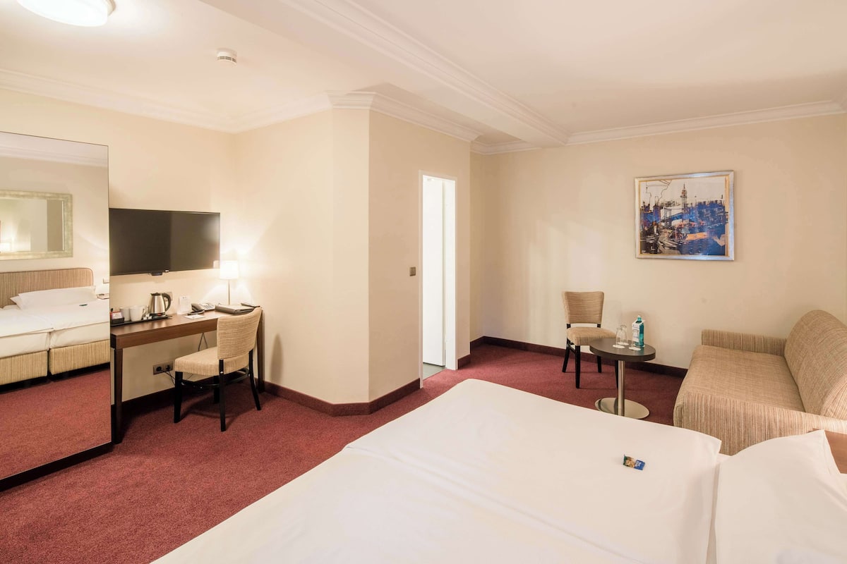 Een hotelkamer met een bed, bureau, stoel en een televisie.