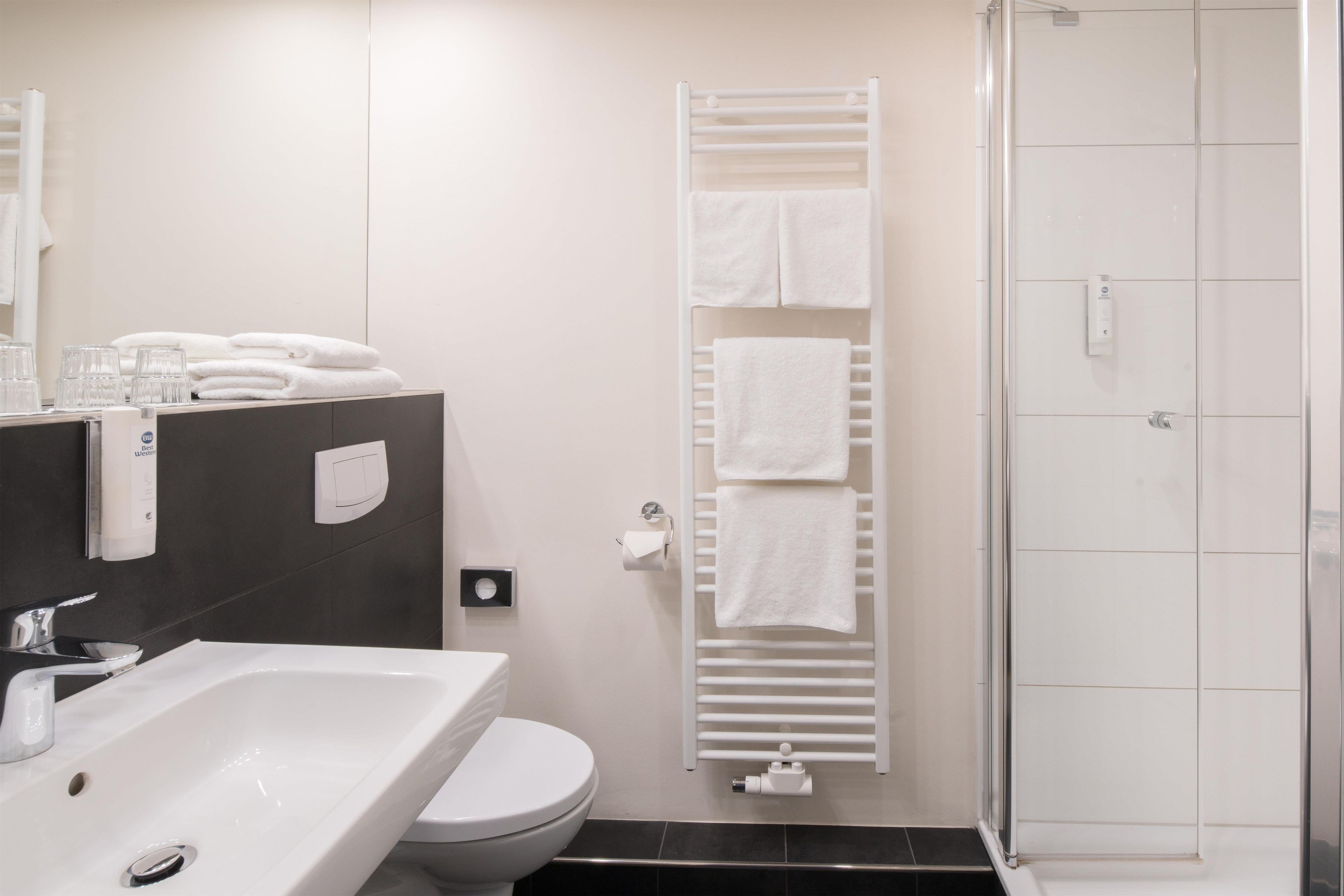 Un baño moderno con un lavabo blanco, inodoro y cabina de ducha de vidrio.