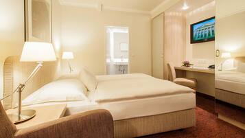 Ein Hotelzimmer mit Bett, Schreibtisch, Stuhl, Fernseher und Spiegel.