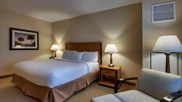 Habitación de hotel con una cama grande, dos mesitas de noche con lámparas, una silla y un cuadro en la pared.