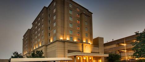 A multi-story hotel with a covered entrance and a parking area.