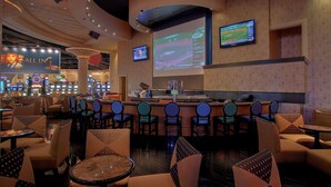 Zona de bar con varias pantallas, asientos y una barra.
