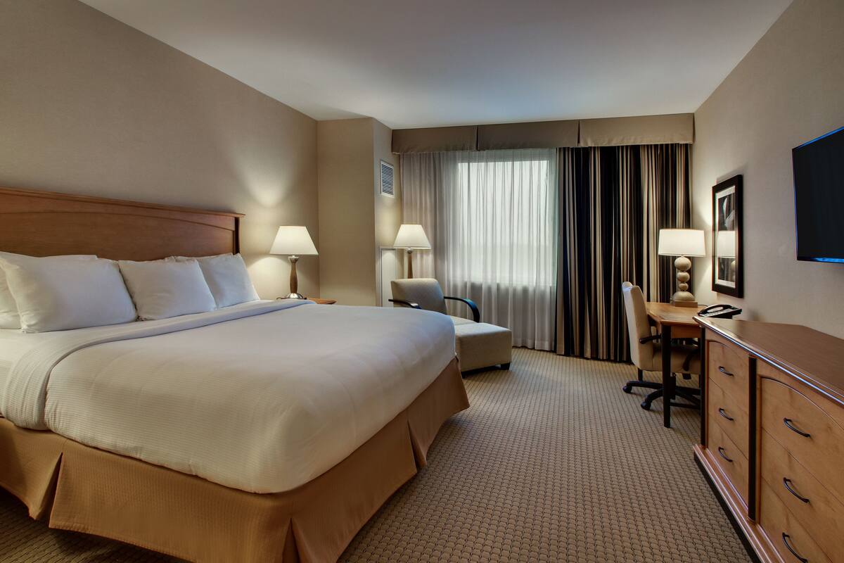 Een hotelkamer met een groot bed, een bureau, een stoel en een televisie.