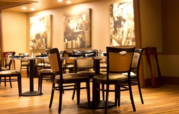 Un restaurante con suelo y mesas de madera, con sillas.