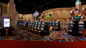 Un salón de casino con máquinas tragamonedas, sillas y letreros de neón.
