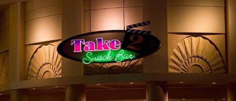 En neonskilte for 'Take 2 Snack Bar' med et klipperbord-design.