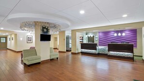 Un hall d’entrée spacieux avec un plancher en bois, un comptoir de réception et deux fauteuils à motifs.