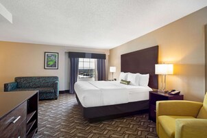 A hotel room with a bed, a sofa, a desk, and a chair.