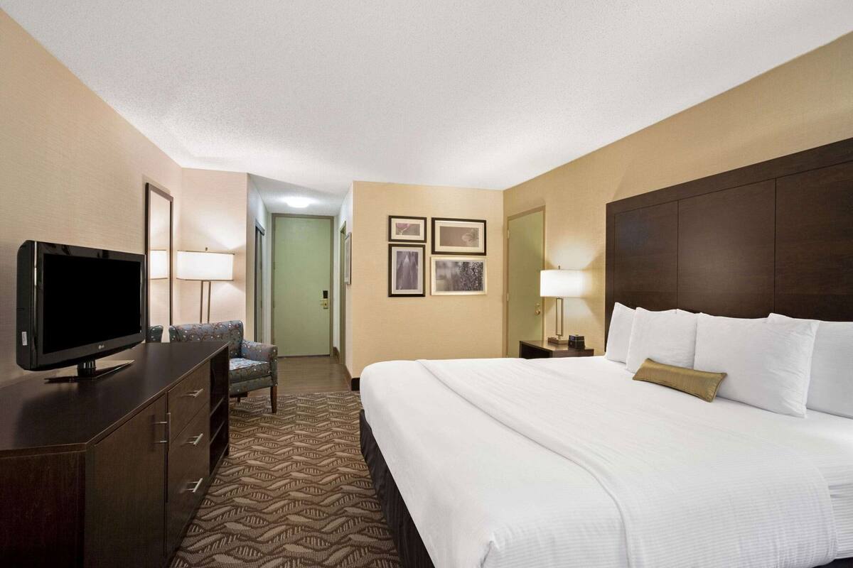 Una habitación de hotel con una cama grande, televisor, escritorio y una silla.