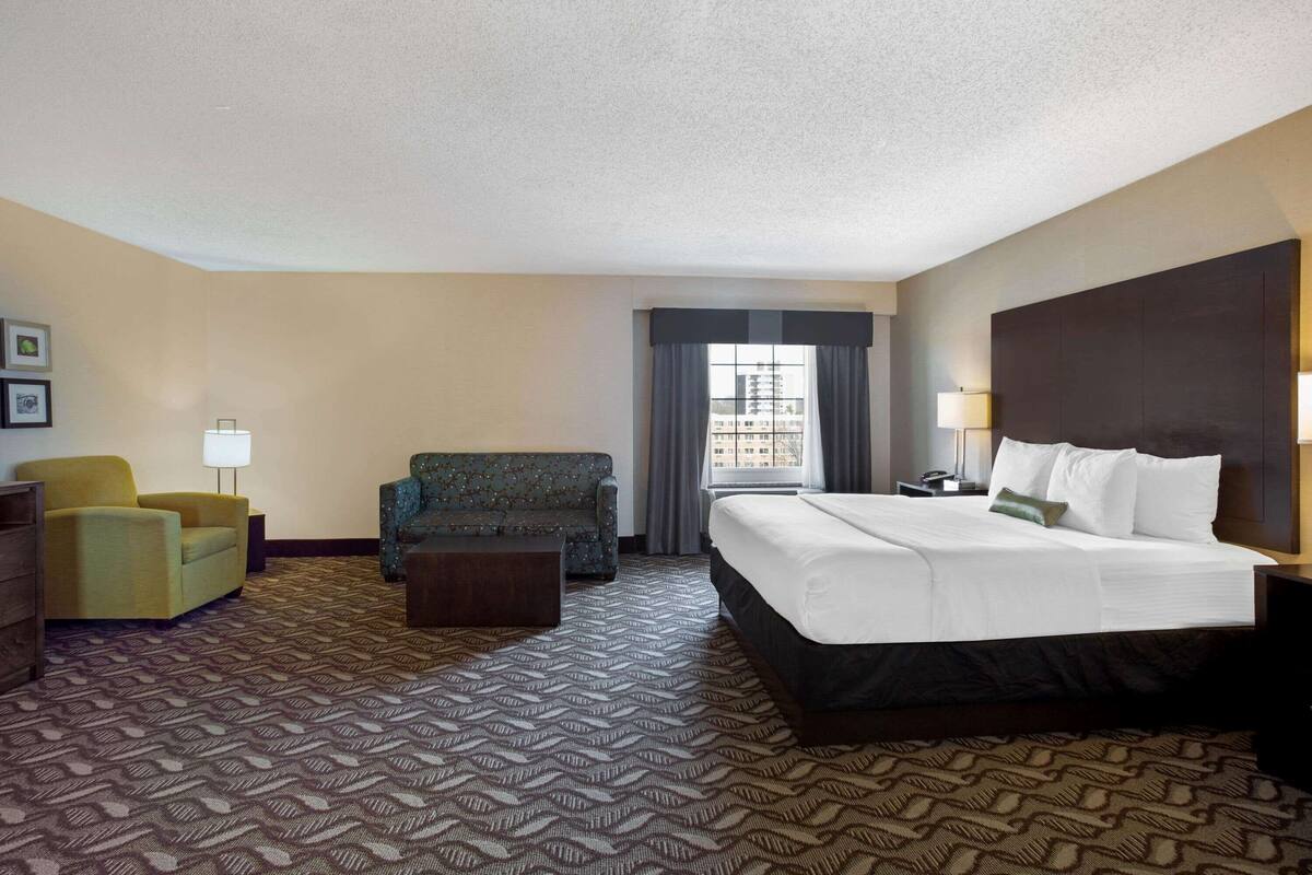 Una habitación de hotel con una cama grande, un sofá, una silla y un escritorio.