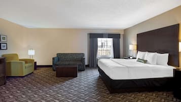 Une chambre d’hôtel avec un grand lit, un canapé, un fauteuil et un bureau.
