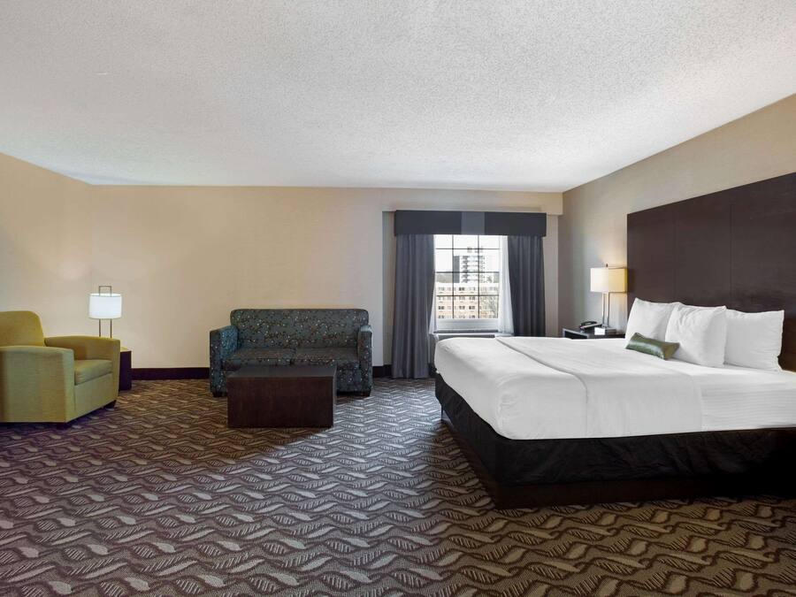 Una habitación de hotel con una cama grande, un sofá, una silla y un escritorio.