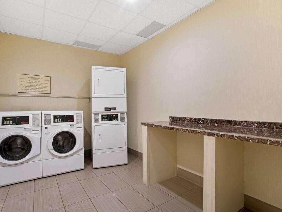 A laundry area with two front-loading washing machines and a stacked dryer.