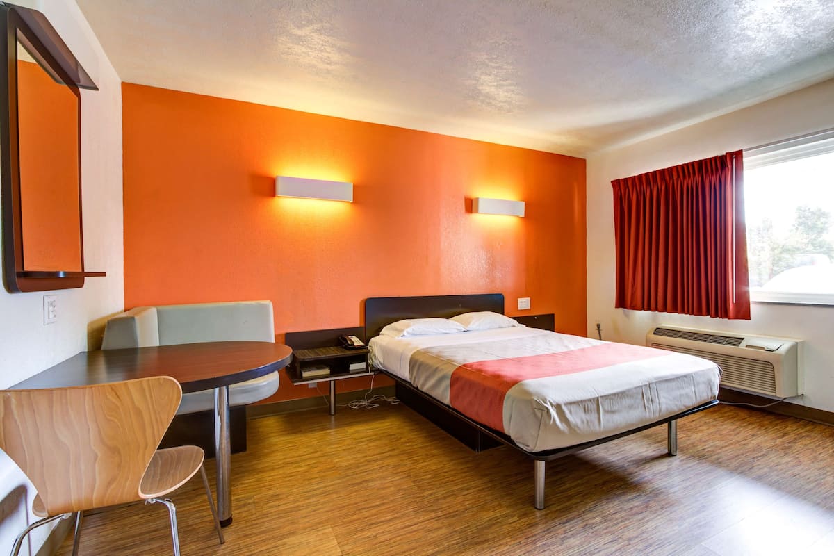 Une chambre d’hôtel équipée d’un lit, d’un bureau, d’une chaise et de deux lampes fixées au mur.