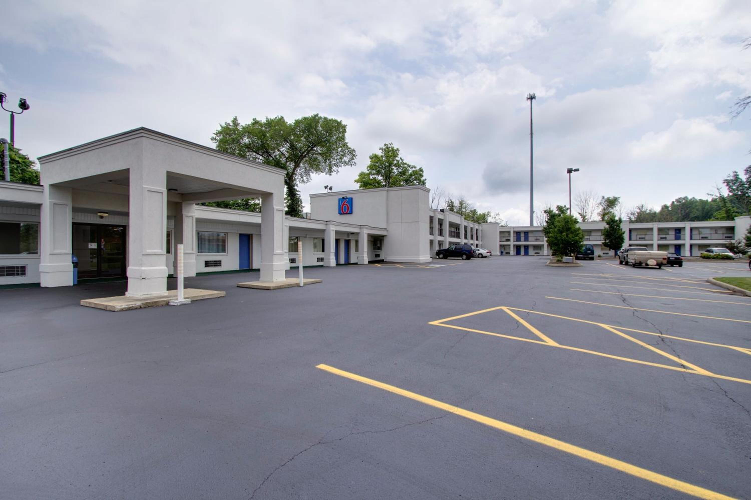 A hotel with a covered entrance, multiple rooms, and a parking lot.